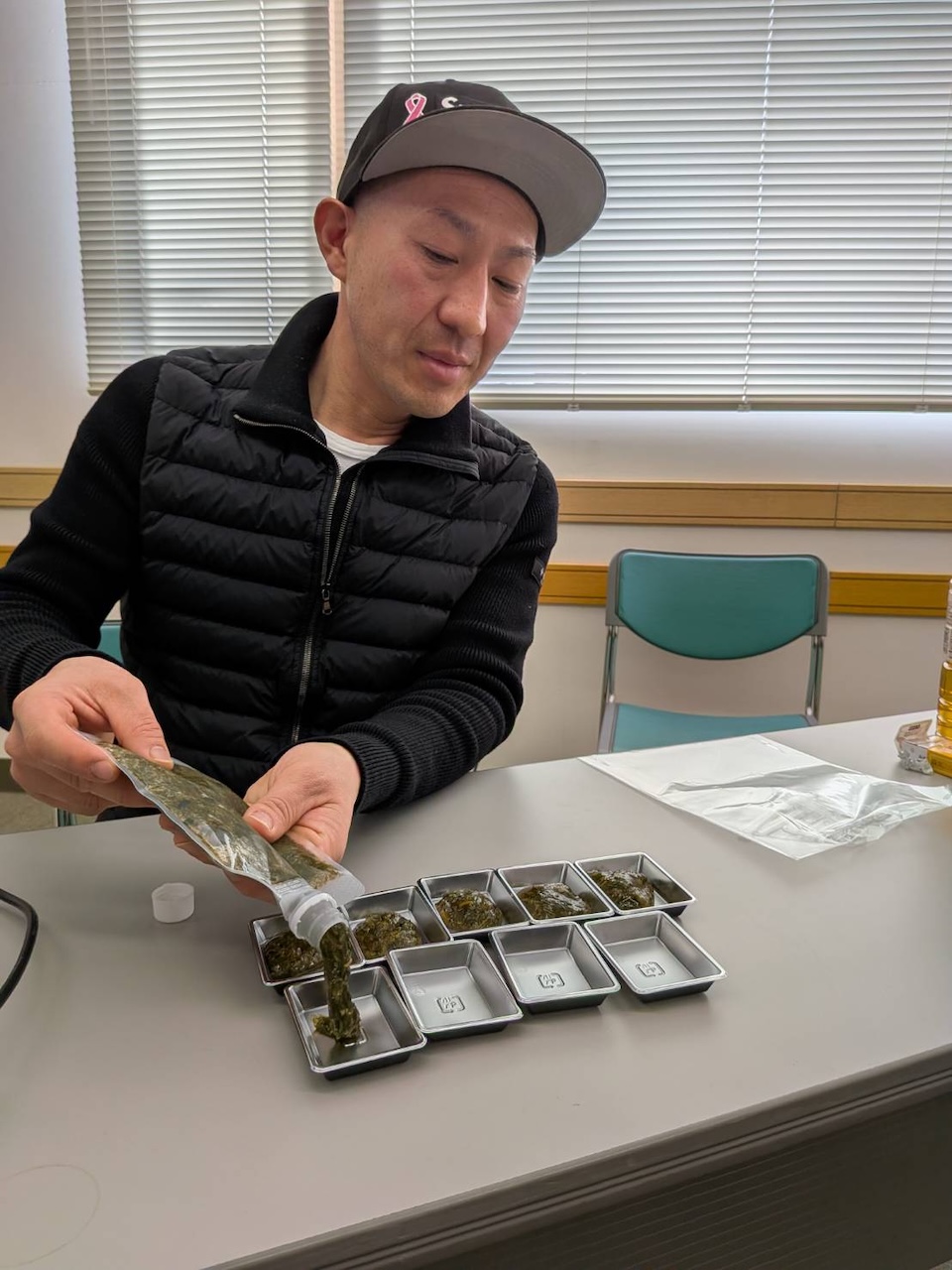 宗像産あかもくの新商品を小分け容器に盛り付け、試食準備をする様子。One Day Meetingの学びの合間の実食シーン(くりえいと)