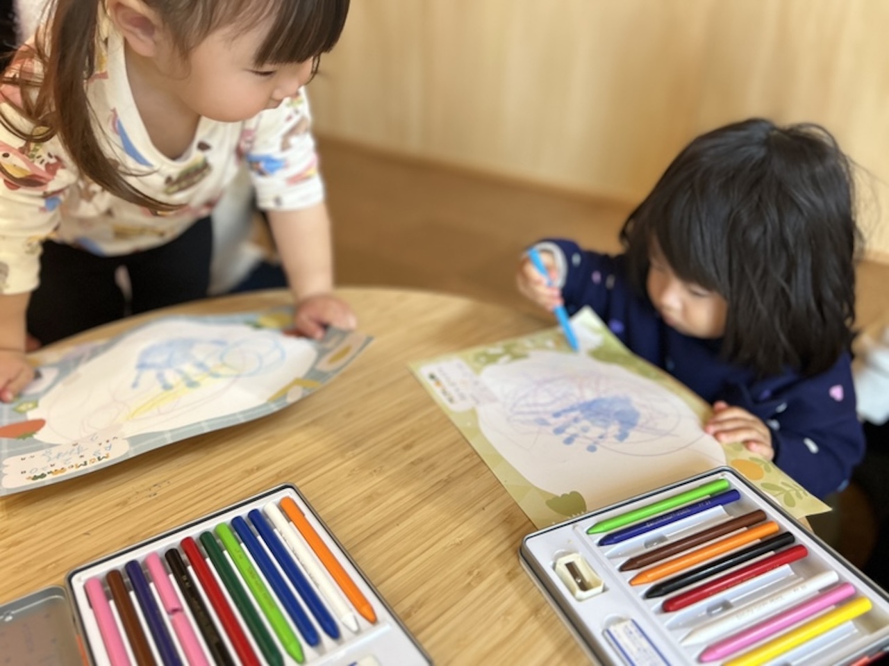Mu-Moのイベント『あんよでぺったん』で、自分の手形の台紙にお絵描きを楽しむこどもたち
