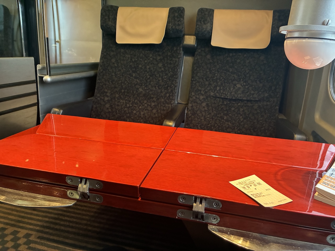 移動中の車内にある赤いテーブル席。日々の移動や働き方の余白を感じさせる一枚