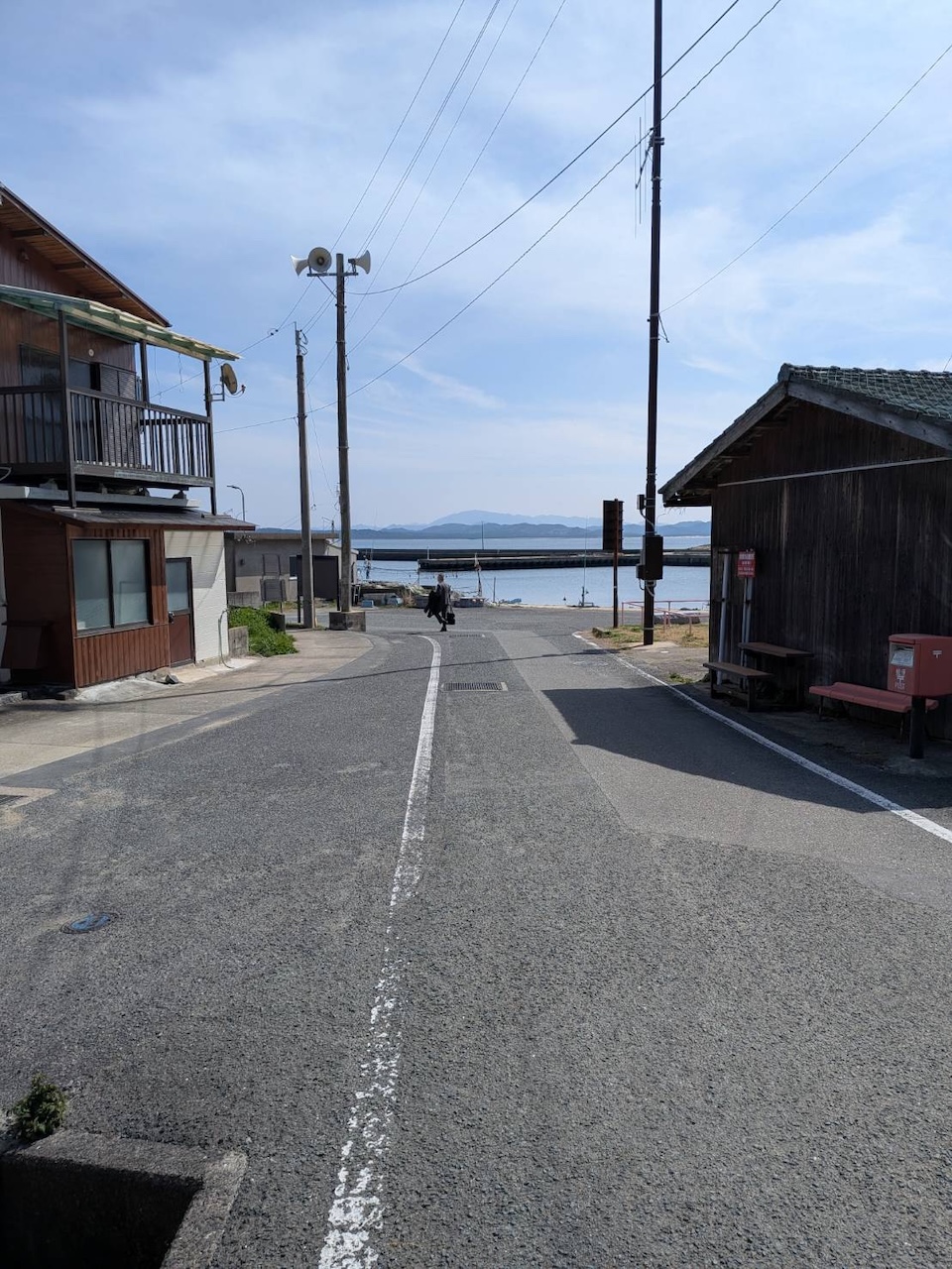 地島の泊地区の集落の坂道から、家並み越しに海を望む風景