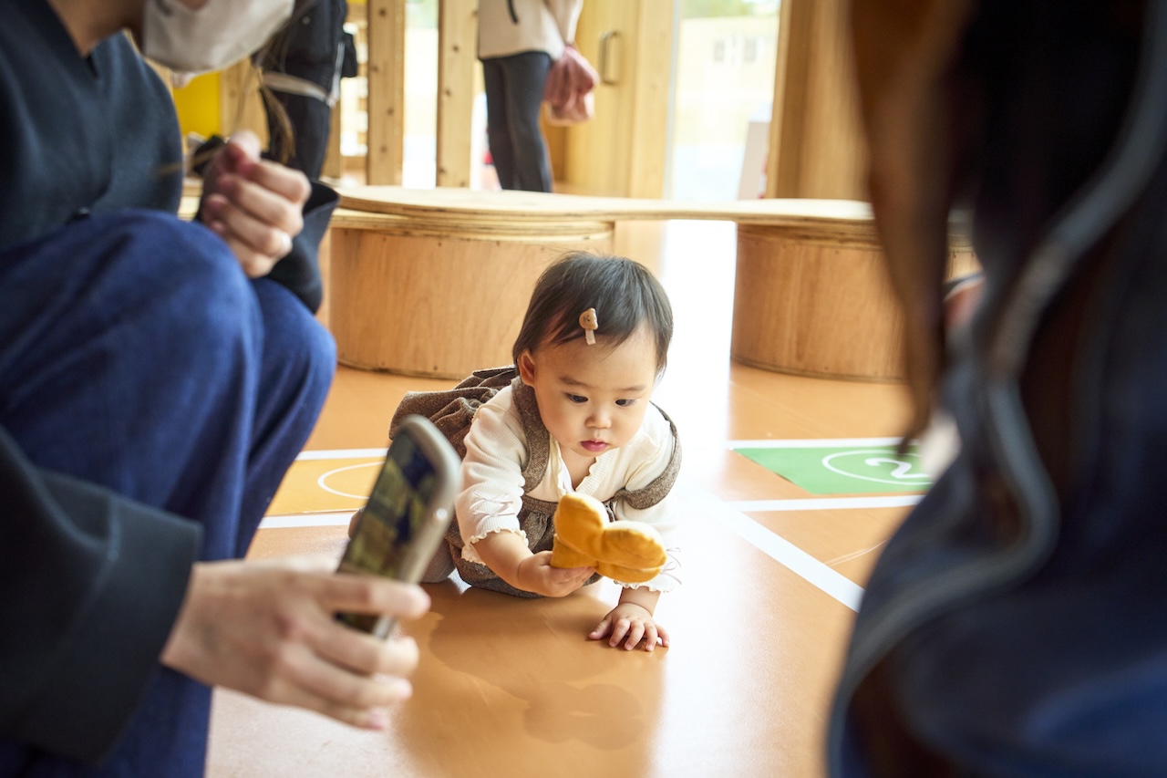 目の前のおもちゃに興味を示しながらレースを楽しむ赤ちゃん