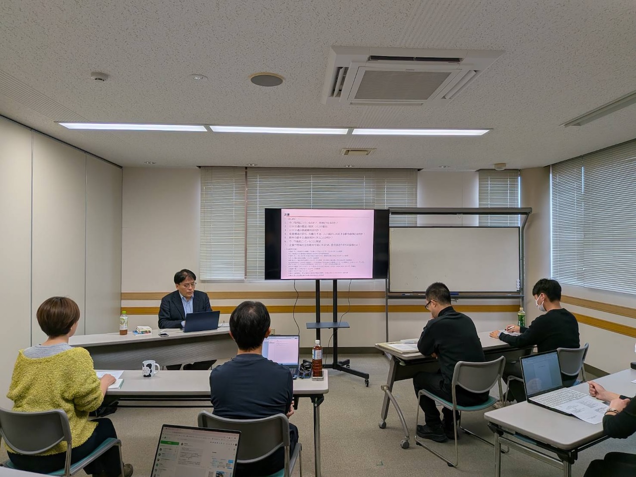 会議室で外部講師の講義を参加者が真剣に聞いているワンデイミーティングの様子