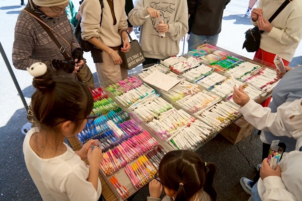 フリーマーケット会場でカラフルな商品を選ぶ子どもたちと来場者