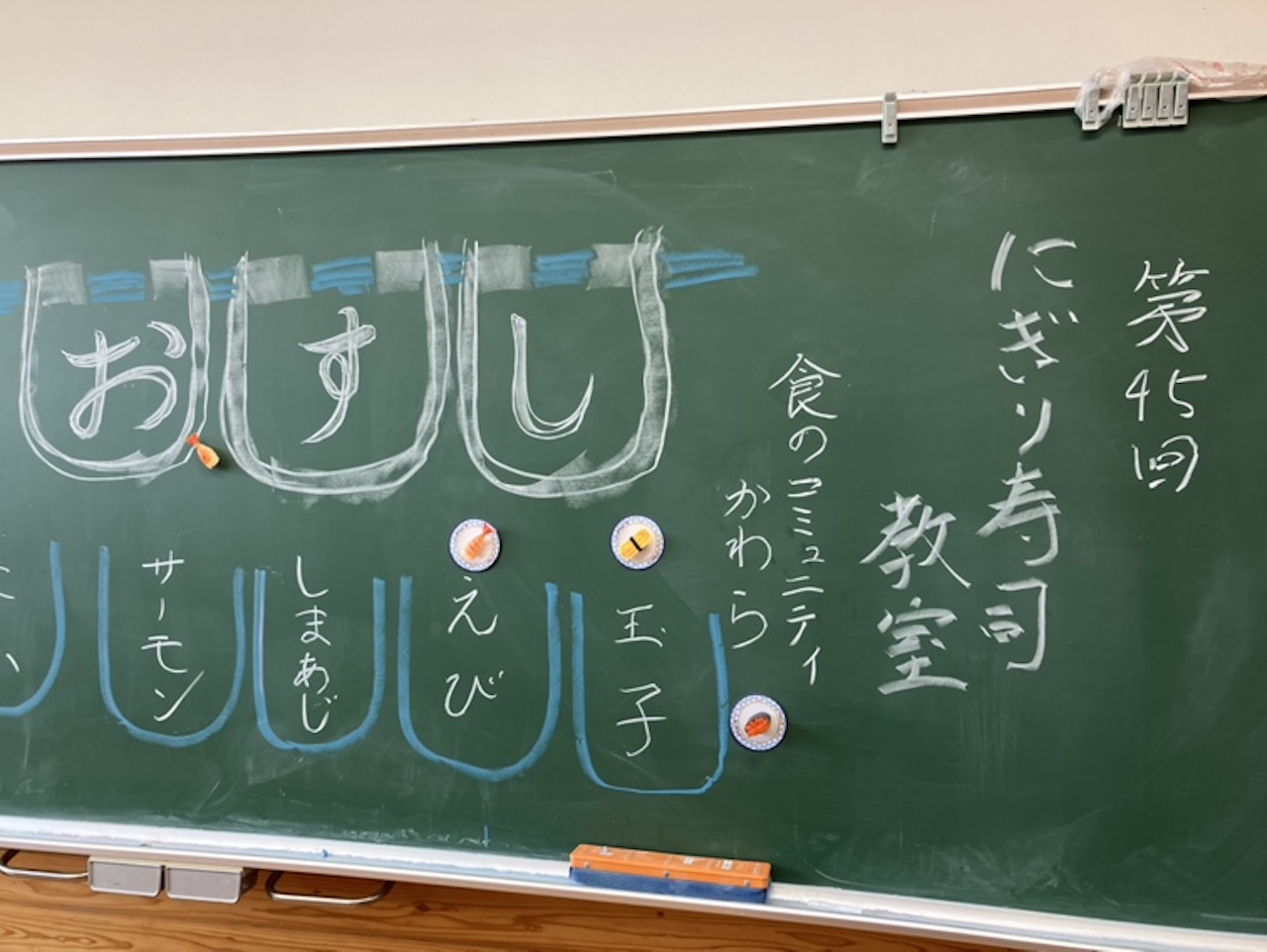 黒板に『おすし』とネタの名前が書かれた握り寿司教室の案内風景