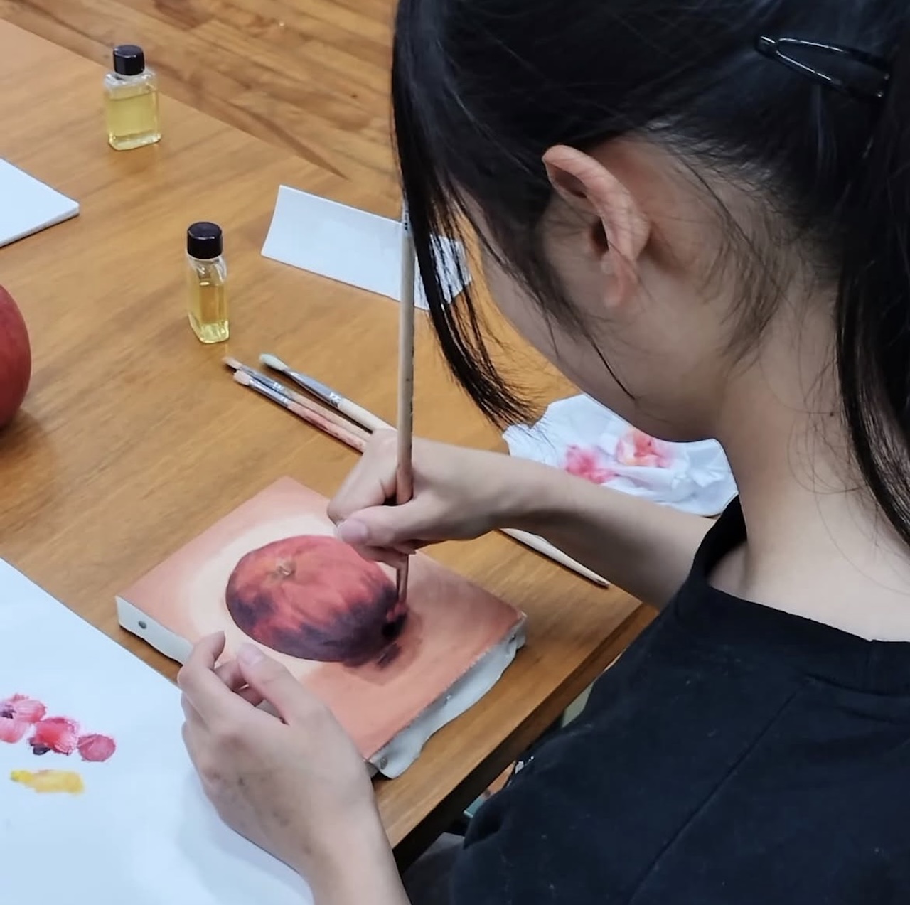 モチーフを見ながら油彩で丁寧に描き進める中学生の制作風景