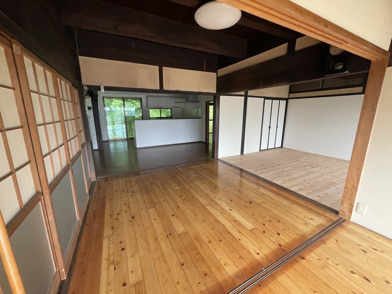 宗像市吉留の古民家シェアハウスの広間。立派な梁とフローリングが特徴で、奥にLDKが見える