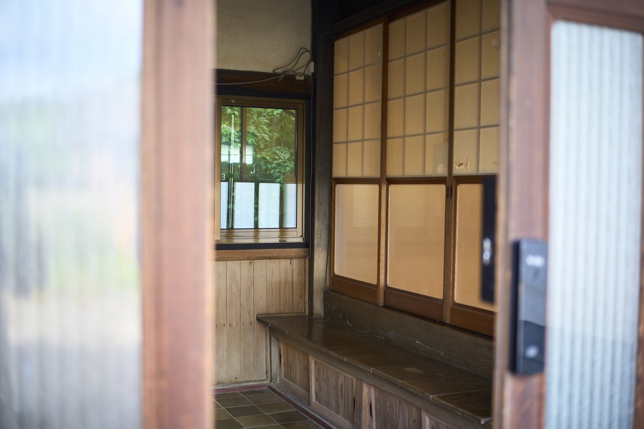 障子と木製建具が並ぶ古民家の玄関内部、スマートロックが取り付けられた引き戸