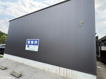 「桜杏」の文字と売物件看板が掲げられた黒い外壁の建物