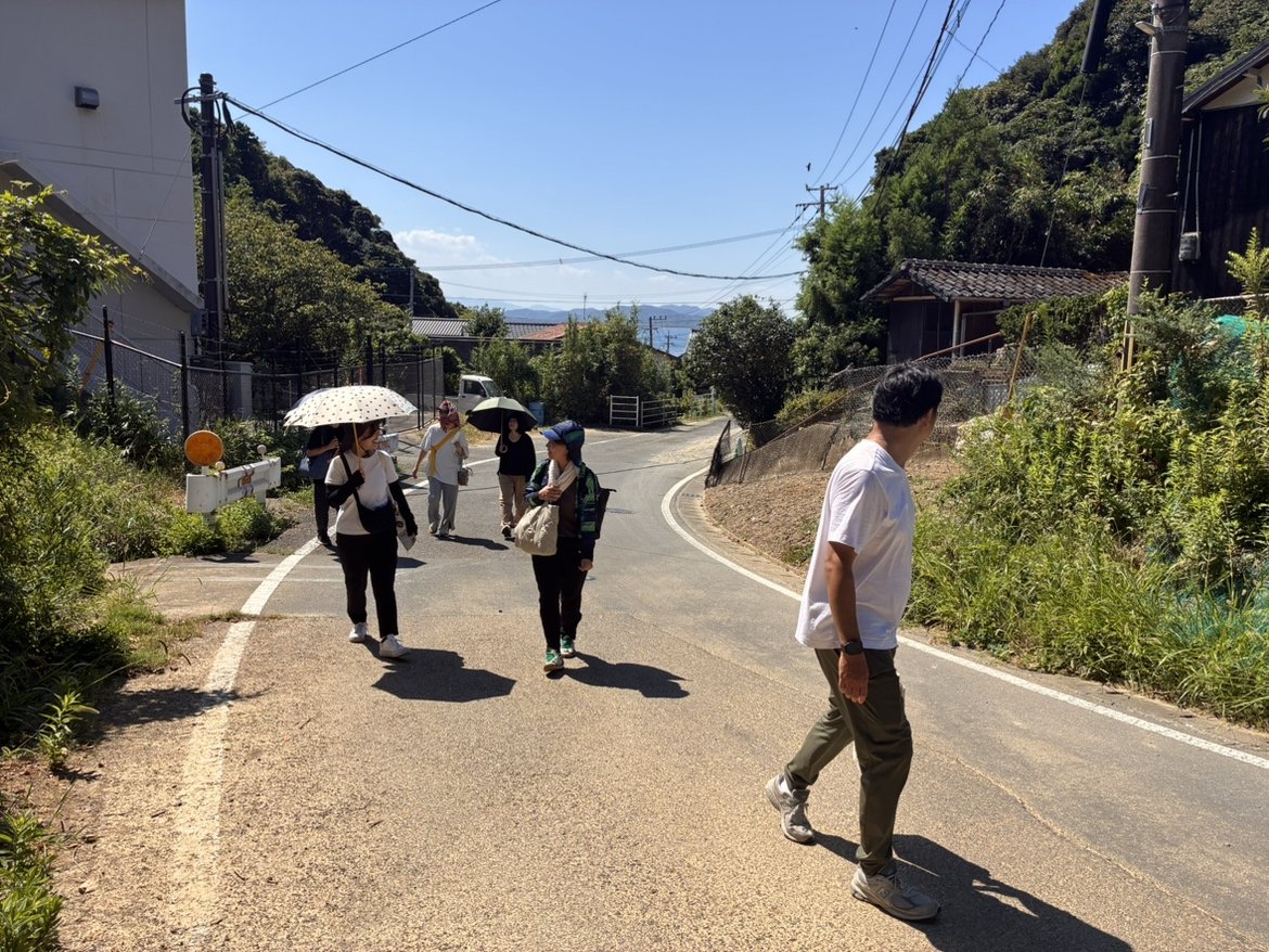 地島の集落内のカーブした道を歩く複数のスタッフ