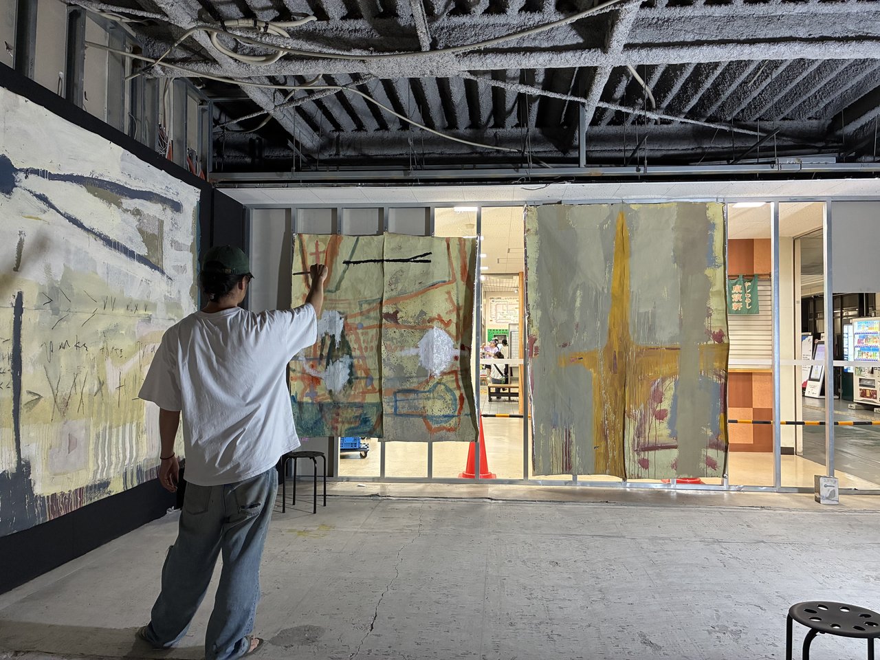赤間駅の展示スペースで抽象画作品の片付け作業をする男性の後ろ姿