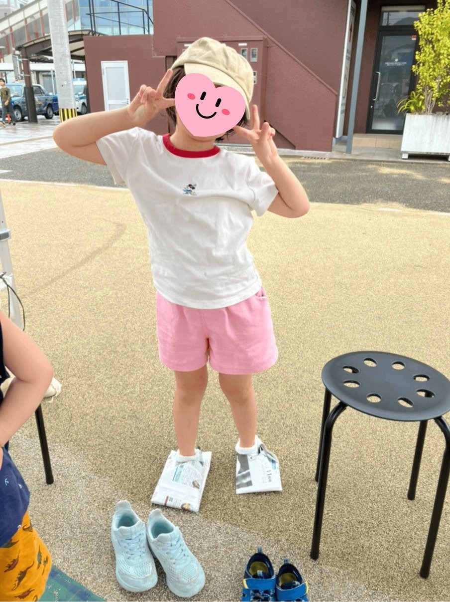 新聞紙で作った防災スリッパを履いてピースサインをする子ども