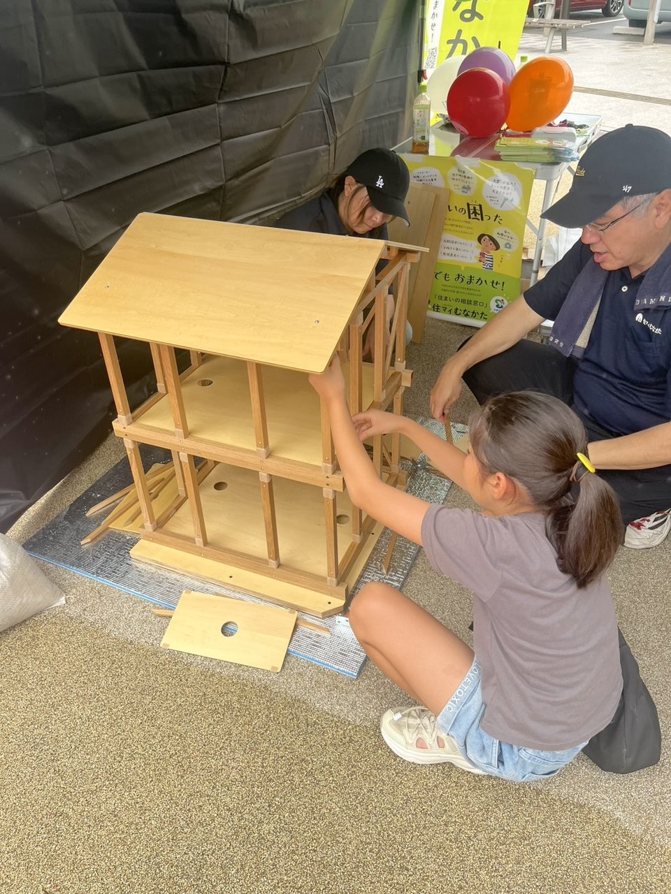 木造建築模型を使って耐震構造を学ぶ子どもとスタッフ