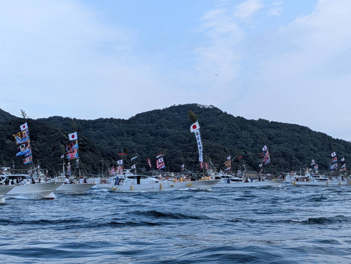 日の丸や大漁旗を掲げた漁船団が海上に並ぶみあれ祭の船渡御の様子