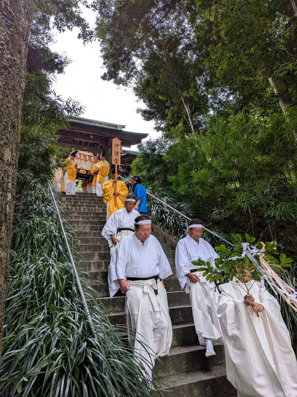 沖津宮の看板を掲げた神職たちが白装束で石段を下りる神事の行列