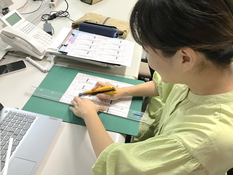 女性スタッフがカッターマットの上で印刷物を裁断している様子