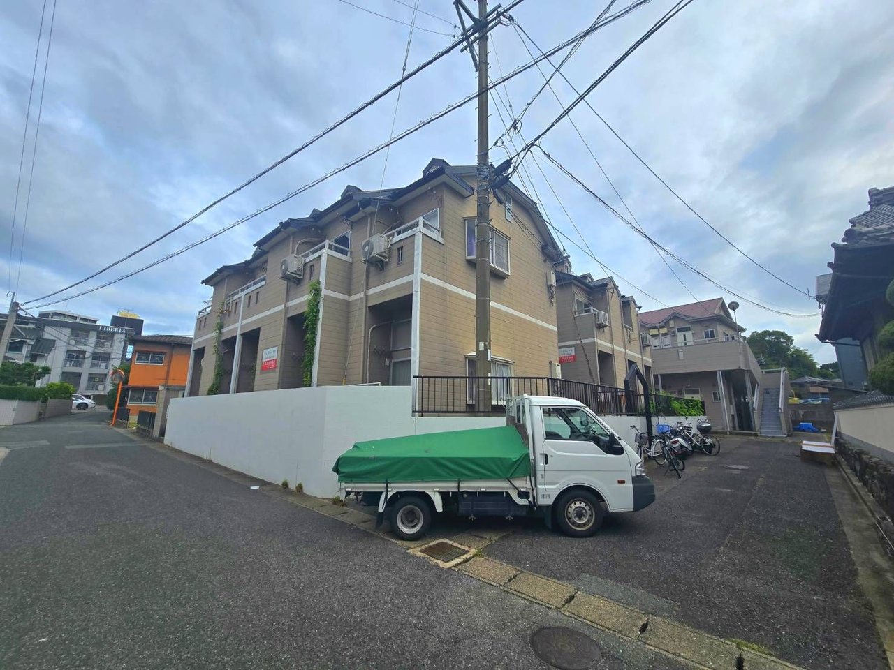 角地に建つ二棟のアパート全景|前面道路と白いトラック